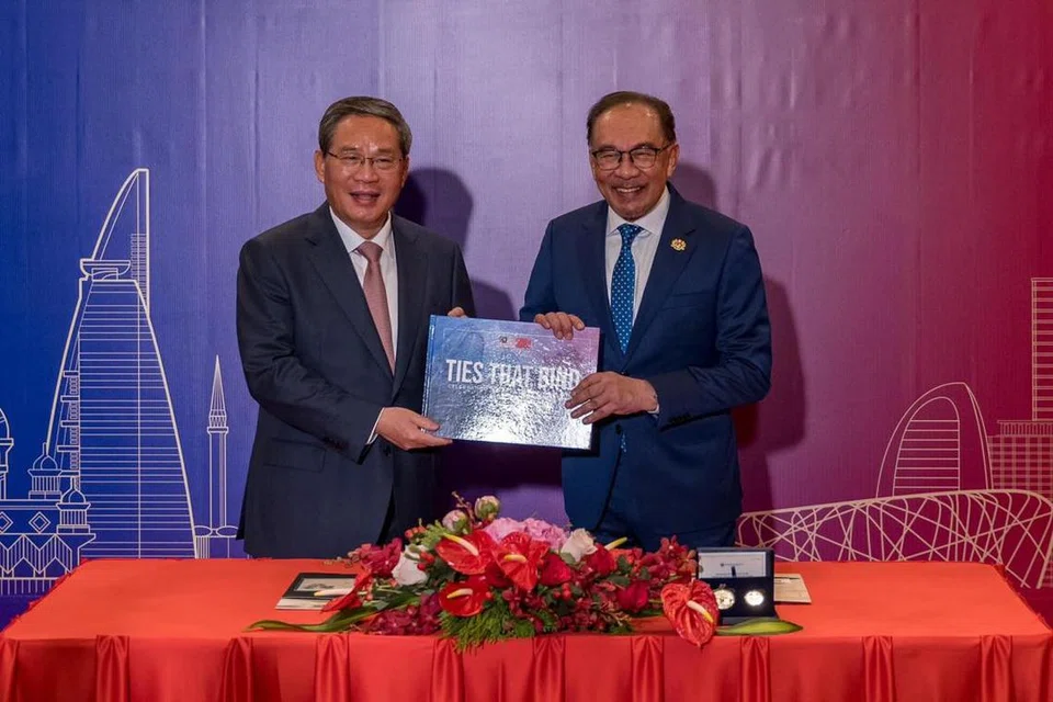 Perdana Menteri Malaysia, Datuk Seri Anwar Ibrahim (kanan), dan Perdana Menteri China, Encik Li Qiang, bertukar-tukar buku mewah bagi memperingati ulang tahun hubungan diplomatik ke-50 antara Malaysia dan China. 