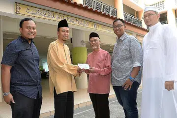 BUKAN SEKADAR IBADAH KORBAN: (Dari kiri) Pengarah Urusan syarikat Imtidad Pte Ltd dan Travel Connect.sg, Encik Zacree Zain; Mudir Madrasah Aljunied Al-Islamiah, Ustaz Mahmoud Mathlub Sidek; Pengerusi Lembaga Pentadbir Madrasah Aljunied Al-Islamiah, Ustaz Pasuni Maulan; Pengurus Besar syarikat yang sama, Encik Noredeen Zain; pembimbing umrah Travel Connect.sg, Ustaz Azmi Rabbani (berbaju putih) dalam acara ringkas penyampaian cek bernilai $15,000 hasil lebihan projek korban di Lombok, Indonesia, tahun lalu kepada Wakaf Ilmu Madrasah Aljunied Al-Islamiah. - Foto JOHARI RAHMAT