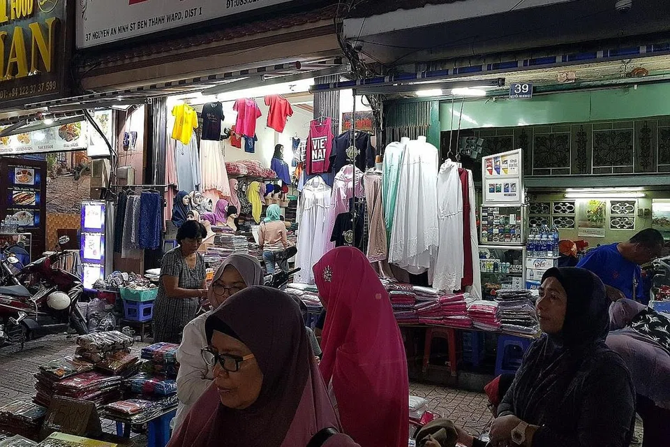 SEMUA ADA: Telekung pelbagai warna dan rekaan sebahagian daripada pelbagai tarikan di luar pasar Ben Thanh pada sebelah malam. Terdapat juga tudung, makanan halal dan buah-buahan segar. - Foto BH oleh NIZAM ISMAIL