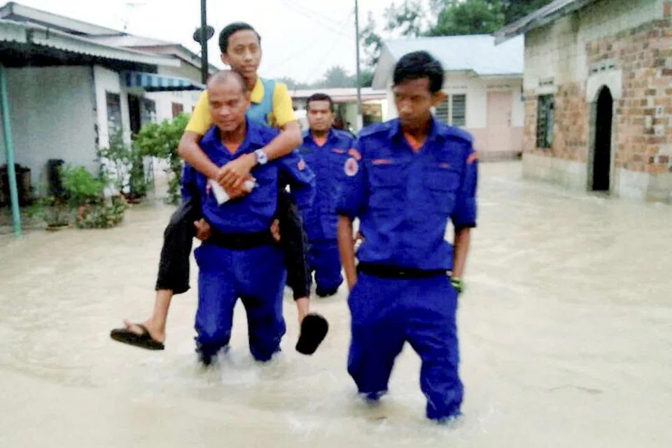 MANGSA BAH MELAKA DIPINDAHKAN: Anggota Angkatan Pertahanan Awam (APM) Malaysia membantu mangsa banjir di Kampung Serkam Pekan di Merlimau. - Foto APM 