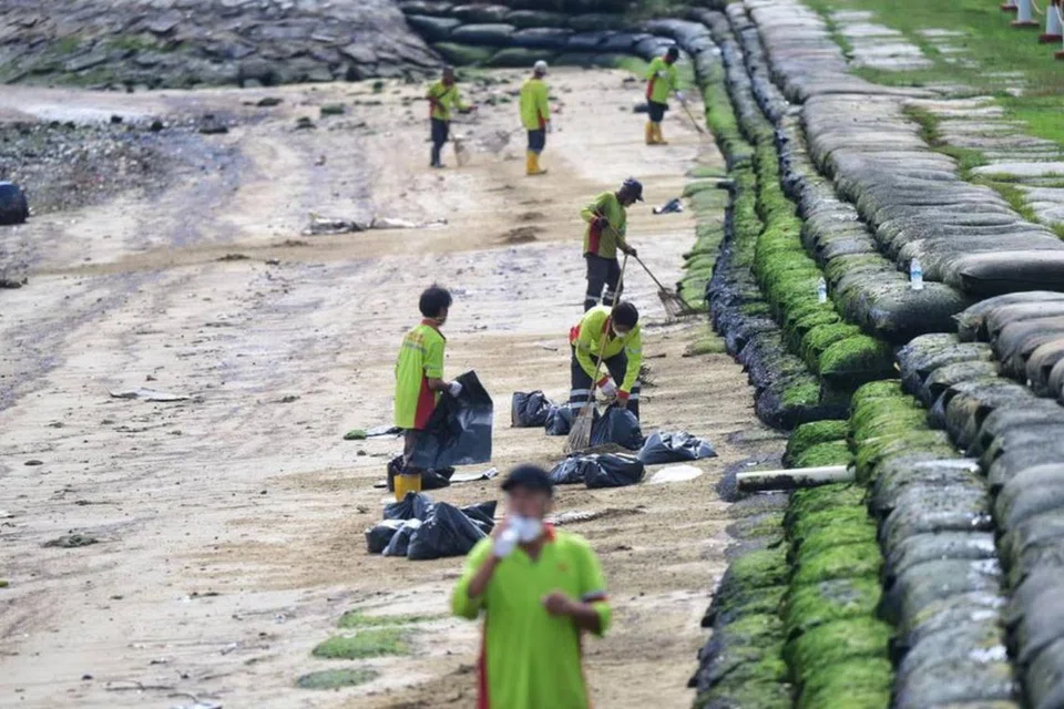 Pekerja sedang membersihkan tumpahan minyak di Kawasan 1 Pantai Pasir Ris pada 4 April.