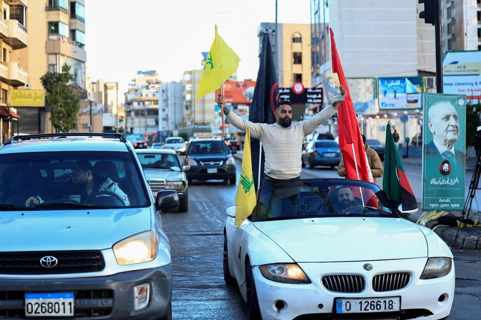 Seorang lelaki di selatan Beirut dilihat mengibarkan bendera Hezbollah selepas Israel dan Hezbollah bersetuju melaksanakan gencatan senjata mulai 27 November.