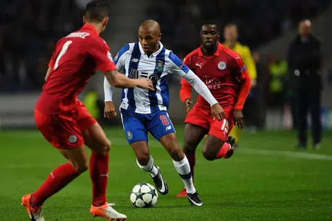 Pemain FC Porto Yacine Brahimi mengawal bola antara pemain pertahanan Luis Hernandez (kiri) dan pemain tengah Ghana Jeff Schlupp Leicester City semasa perlawanan Kumpulan G Liga Juara-Juara di Stadium Dragao di Porto pada 7 Disember 2016 . 