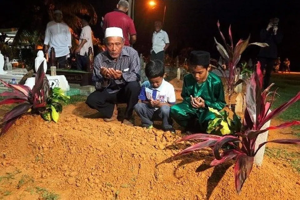 SELAMAT DIKEBUMIKAN: Datuk Allahyarham Mohamad Thaqif, Encik Ahmad Motai (kiri), membaca doa selepas pengebumian cucunya di Tanah Perkuburan Islam Felda Bukit Aping Timur di Kota Tinggi, awal pagi semalam. - Foto NSTP