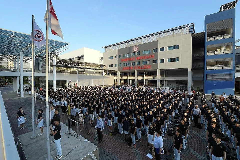BENDERA SEKOLAH BARU: Para pelajar dan kakitangan Maktab Rendah Tampines Meridian (TMJC) berdiri penuh hormat semasa bendera baru TMJC dikibarkan seiringi bendera kebangsaan semasa perhimpunan pagi di hari pertama sekolah mereka semalam. - Foto BH oleh ALPHONSUS CHERN