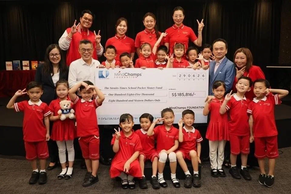 Editor ST, Encik Jaime Ho (barisan tengah, dua dari kiri) menerima sumbangan cek daripada pengasas MindChamps, Encik David Chiem.
