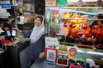 PERNIAGAAN LAMA GUNA TEKNOLOGI BARU: Gerai Putri Hana yang asalnya ditubuhkan lebih empat dekad lalu dan kini dikendali penjaja generasi kedua, Cik Rokiah Hamzah, menawarkan khidmat e-pembayaran melalui kaedah Kod Respons Pantas Singapura (SGQR) sejak tahun lalu. - Foto BM oleh JASON QUAH