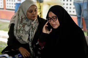 Cik Norazian Mohd Joned (kanan), isteri Allahyahram Koperal Amiruddin Zabri yang terlibat dalam kemalangan di Jalan Chikus, Perak tidak dapat menahan sebak ketika hadir di luar Unit Forensik Hospital Teluk Intan pada 13 Mei. 