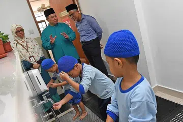 DIDIK SEJAK KECIL: Encik Masgos diberi taklimat oleh Pengerusi Eksekutif Masjid Mujahidin, Encik Muhammad Khairul Jameel Yahya, mengenai kanak-kanak di tadika Masjid Mujahidin yang diajar cara mengambil wuduk dengan melakukannya secara menjimatkan air. - Foto BH oleh DESMOND FOO
