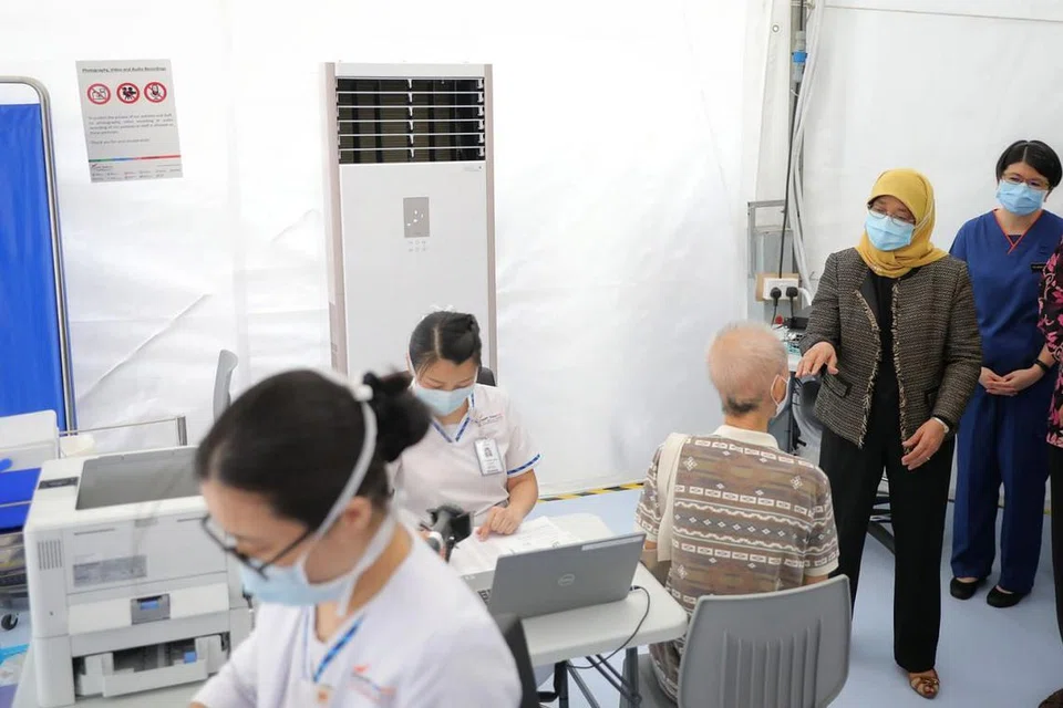 MANFAAT VAKSIN: Presiden Halimah Yacob sempat meluangkan masa untuk bermesra dengan beberapa warga emas di hab vaksinasi di Poliklinik Outram. Beliau turut menerima dos pertama vaksin Covid-19 semalam. - Foto BH oleh ONG WEE JIN