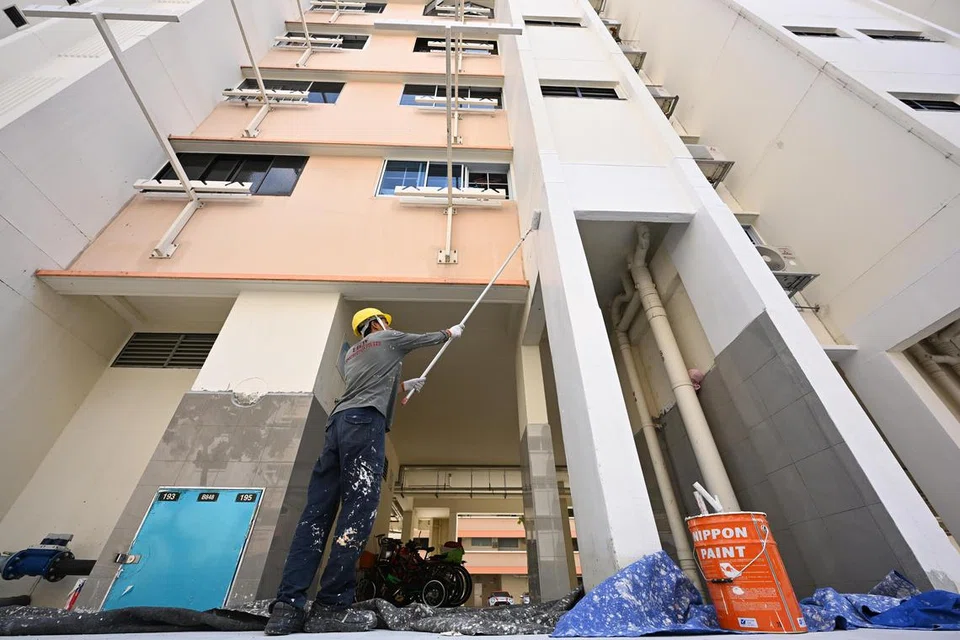 Seorang pekerja menggunakan cat pantul haba di Blok 848 Tampines Street 82. Skim ini akan ditawarkan kepada semua majlis bandaran dalam tempoh lima tahun akan datang, dan kos cat baru itu akan ditanggung pemerintah.