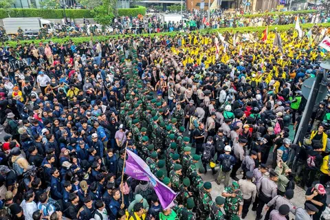 Anggota Tentera Nasional Indonesia (TNI) berdiri di belakang anggota polis bagi menghalang laluan mahasiswa yang mengadakan demonstrasi menuntut penurunan harga bahan api serta pembubaran program makanan berkhasiat percuma Presiden Prabowo Subianto yang didakwa berpotensi menjadi ruang berlakunya rasuah, di Jakarta pada 12 Jun.
