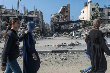 Para penduduk Palestin berjalan sambil melihat bangunan-bangunan kediaman yang runtuh di kem perlindungan di Al-Nuseirat akibat serangan udara Israel pada 28 Februari.