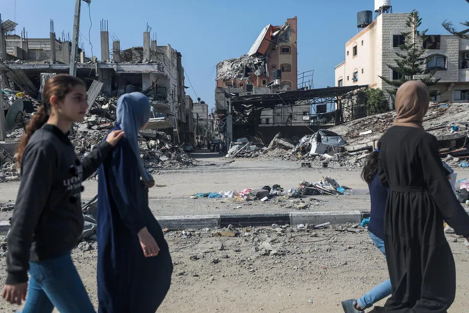 Para penduduk Palestin berjalan sambil melihat bangunan-bangunan kediaman yang runtuh di kem perlindungan di Al-Nuseirat akibat serangan udara Israel pada 28 Februari.