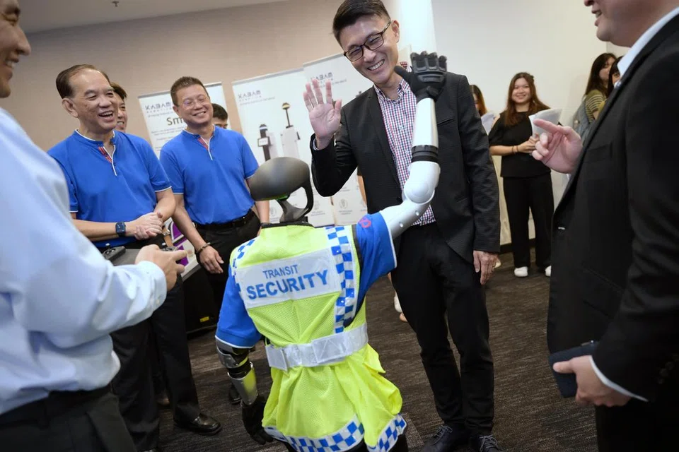 Setiausaha Parlimen Kanan (Pengangkutan), Encik Baey Yam Keng, berinteraksi dengan robot humanoid pengawasan SBS Transit.