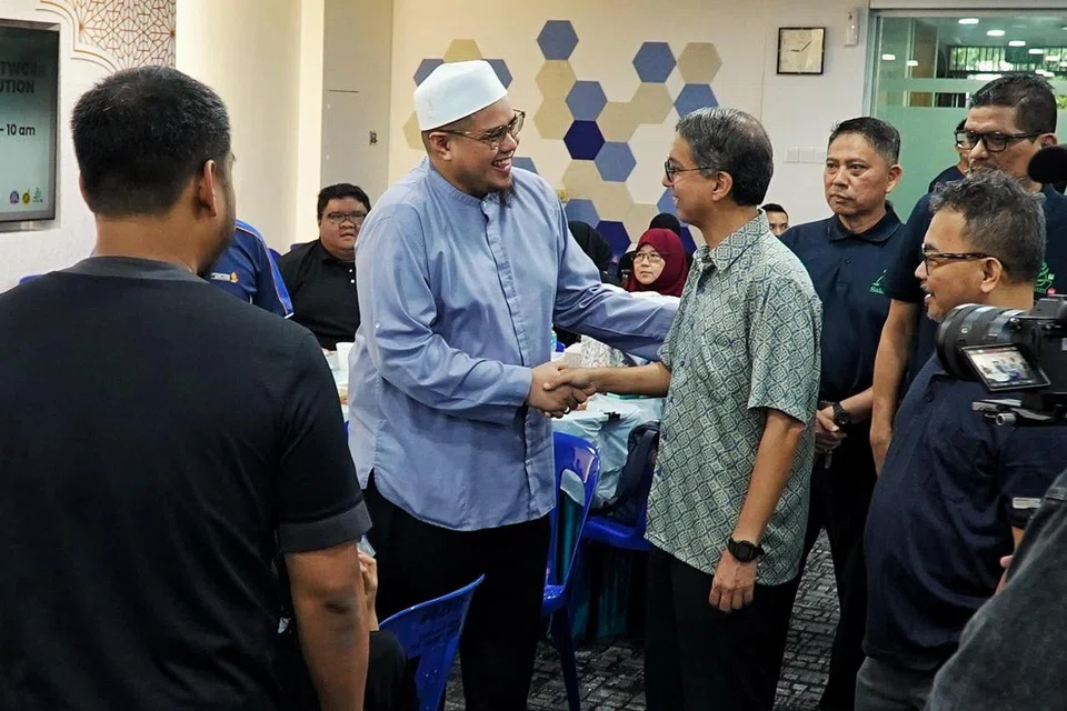 Ustaz Zulhilmi Mohamed, Pengarah Eksekutif Perdaus (bersongkok) bersalaman dengan Profesor Madya Dr Muhammad Faishal Ibrahim semasa acara Pengagihan Daging Korban Rangkaian Pemulihan Badan Melayu/Islam di Masjid An-Nur pada 29 Jun.