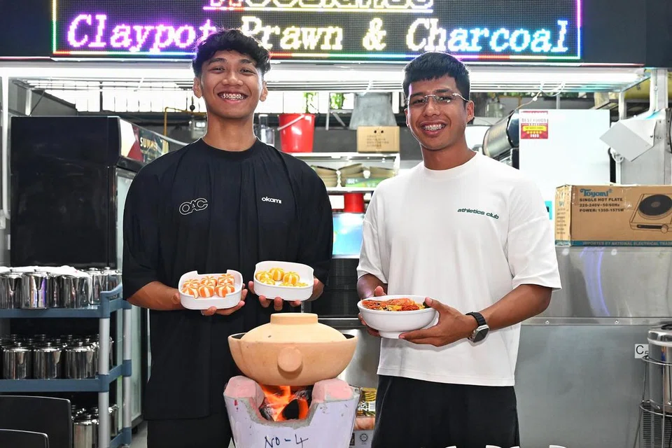 Rakan kongsi gerai Steamboat Charcoal Claypot Prawn, Encik Khairulanwar Razali, 23 tahun (kiri), dan Encik Sheqal Armanda Sabarrudin, 26 tahun (kanan), di gerai mereka di Toa Payoh.