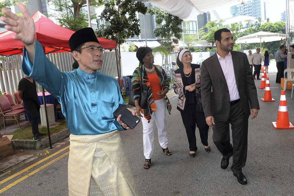MENYAMBUT TETAMU: Dr Maliki (kiri) menyambut kedatangan Konsul Am Oman ke Singapura, Encik Zakariya Hamed Hilal AlSaadi, (kanan) dan beberapa diplomat lain yang hadir pada majlis Rumah Terbuka Hari Raya Aidilfitri anjuran beliau. - Foto TAUFIK A. KADER