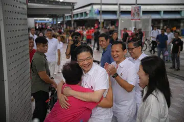 Perdana Menteri, Encik Lawrence Wong (didakap seorang penduduk) bersama anggota lain pasukan GRC Marsiling-Yew Tee (dari kanan) Cik Hany Soh, Encik Alex Yam dan Encik Zaqy Mohamad di Pasar Marsiling pada 4 Mei.