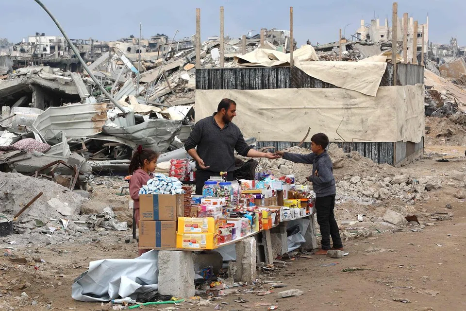 Seorang lelaki menjual barangan di hadapan runtuhan bangunan yang musnah di sepanjang jalan Saftawi di Jabalia, utara Gaza pada 5 Februari semasa perjanjian gencatan senjata antara Israel dengan Hamas. 