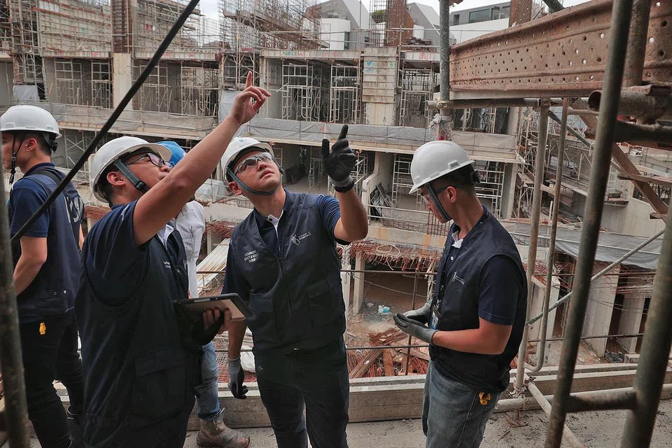 PEMERIKSAAN MENGEJUT: Encik Zaqy (dua dari kanan) mengikuti pemeriksa WSH MOM yang sedang menjalankan pemeriksaan di sebuah tapak pembinaan di Ang Mo Kio semalam - Foto BH oleh JASON QUAH