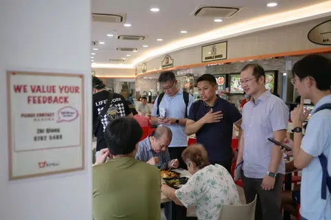 Pengurus hartanah kanan di Majlis Perbandaran Aljunied-Hougang, Encik Abdul Muhaimin Abdul Malik (berbaju biru gelap), dilihat beramah tamah dengan penduduk di Kedai Makanan Koufu di 263 Compassvale Street pada 5 April. Beliau turut ditemani Anggota Parlimen (AP) Parti Pekerja (WP) GRC Sengkang, Encik Louis Chua (dua dari kanan).