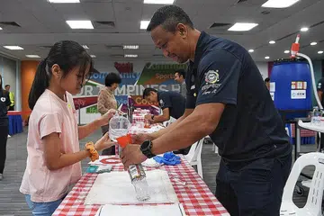 HULUR BANTUAN: Kakitangan Persatuan Bola Sepak Singapura (FAS) termasuk ketua jurulatih belia elit nasional, Fandi Ahmad (kanan), mengagihkan sanitiser tangan percuma kepada penduduk di Our Tampines Hub pada Selasa lalu. - Foto BM oleh KHALID BABA 