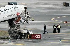 Para pegawai daripada Lembaga Keselamatan Pengangkutan Kebangsaan menjalankan pemeriksaan ke atas bangkai pesawat Air Canada di Lapangan Terbang LaGuardia di Queens, New Yorik, Amerika Syarikat, pada 23 Mac 2026. 
