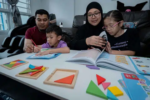 Cik Mardiana Idrus (dua dari kanan) bersama suaminya, Encik Mohammad Jufri Ramli, 40 tahun, sama-sama melakukan aktiviti eKelasMateMatika (eKMM) bersama anak mereka.