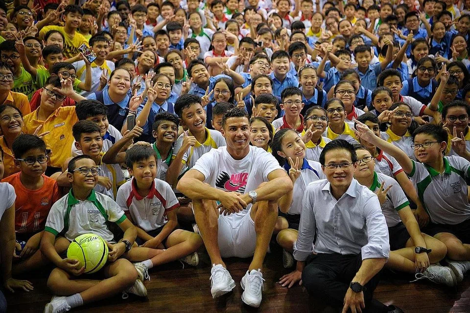 SEBAR INSPIRASI: Ronaldo (tengah) bersama (kirinya) Mayor Daerah North East, Encik Desmond Choo, bergambar dengan pelajar Sekolah Rendah Yumin dan Sekolah Rendah Chongzheng semasa lawatannya ke Sekolah Rendah Yumin semalam. Lawatan ke sekolah itu adalah sebahagian daripada usaha menyokong Biasiswa Yayasan Olimpik Singapura (SOF)-Peter Lim. - Foto BH oleh MARK CHEONG