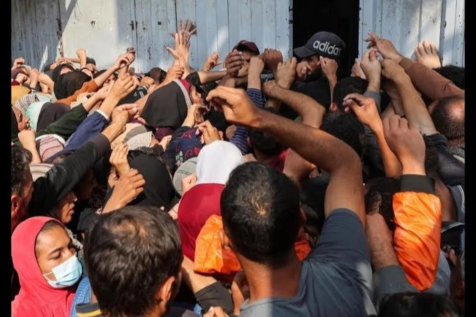 Rakyat Palestin berasak-asak untuk membeli roti dari sebuah kedai di tengah Jaluran Gaza pada 10 November.