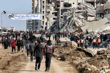 Penduduk Gaza dilihat berkumpul berhampiran kain rentang yang mengalu-alukan kepulangan penduduk berhampiran runtuhan bangunan di sepanjang Jalan al-Rashid, Gaza, pada 26 Januari. Lokasi ini menjadi laluan bagi mereka yang melintasi Koridor Netzarim, yang sebelum ini disekat oleh Israel, dari bahagian selatan Gaza menuju ke Bandar Gaza.