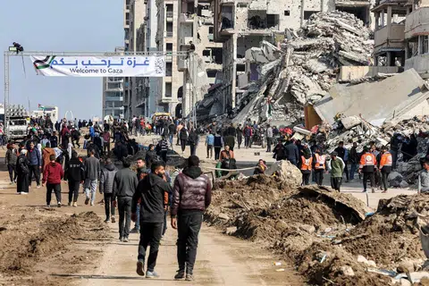 Penduduk Gaza dilihat berkumpul berhampiran kain rentang yang mengalu-alukan kepulangan penduduk berhampiran runtuhan bangunan di sepanjang Jalan al-Rashid, Gaza, pada 26 Januari. Lokasi ini menjadi laluan bagi mereka yang melintasi Koridor Netzarim, yang sebelum ini disekat oleh Israel, dari bahagian selatan Gaza menuju ke Bandar Gaza.