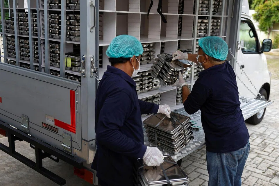 Para petugas memuatkan kotak makanan ke dalam lori untuk diedarkan secara percuma kepada kanak-kanak dan ibu hamil di sebuah dapur di Jakarta, Indonesia, pada 6 Januari.