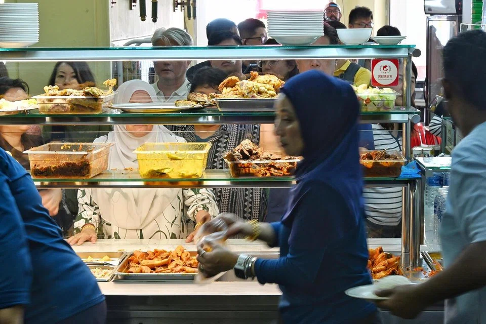 Kakitangan di Warong Nasi Pariaman menghidang makanan kepada pelanggan yang mula beratur seawal 6.30 pagi.
