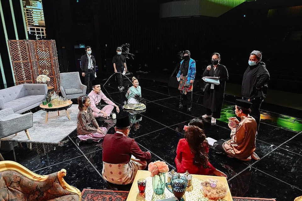 MENGUJI DAYA BINGKAS: Penerbit eksekutif Mediacorp Eaglevision, Cik Fadila Abdul Wahid (berdiri paling kanan dan berpelitup) dan pasukan penerbitan 'Sinar Lebaran 2020' diuji dengan kecekapan dan kespontanan membuat perubahan logistik dan urusan artis apabila tempoh pemutus litar wabak Covid-19 berkuatkuasa dan menjejas proses penerbitan. Beliau bersama artis setempat yang terlibat dalam sketsa komedi mengamalkan undang-undang jarak selamat di studio.