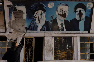 Seorang pekerja menurunkan gambar mantan Presiden Syria, Bashar al-Assad, yang digulingkan; mantan presiden Hafez al-Assad; mantan pemimpin Hezbollah Lebanon yang meninggal dunia, Encik Sayyed Hassan Nasrallah; dan pemimpin tertinggi Iran, Ayatollah Ali Khamenei, di sebuah kedai minyak di Nubl, sebuah perkampungan Syiah yang dirampas oleh pemberontak, di kawasan pedalaman Aleppo pada 11 Disember.