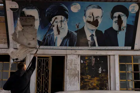 Seorang pekerja menurunkan gambar mantan Presiden Syria, Bashar al-Assad, yang digulingkan; mantan presiden Hafez al-Assad; mantan pemimpin Hezbollah Lebanon yang meninggal dunia, Encik Sayyed Hassan Nasrallah; dan pemimpin tertinggi Iran, Ayatollah Ali Khamenei, di sebuah kedai minyak di Nubl, sebuah perkampungan Syiah yang dirampas oleh pemberontak, di kawasan pedalaman Aleppo pada 11 Disember.