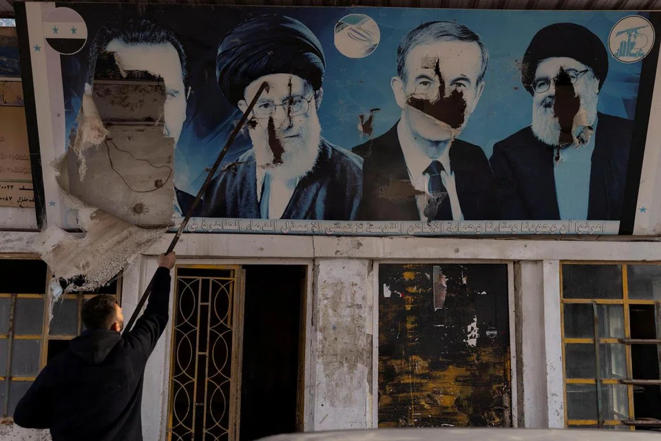 Seorang pekerja menurunkan gambar mantan Presiden Syria, Bashar al-Assad, yang digulingkan; mantan presiden Hafez al-Assad; mantan pemimpin Hezbollah Lebanon yang meninggal dunia, Encik Sayyed Hassan Nasrallah; dan pemimpin tertinggi Iran, Ayatollah Ali Khamenei, di sebuah kedai minyak di Nubl, sebuah perkampungan Syiah yang dirampas oleh pemberontak, di kawasan pedalaman Aleppo pada 11 Disember.