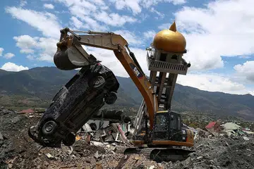 KERJA-KERJA PEMULIHAN: Mesin pengorek memindahkan sebuah kereta yang rosak bersebelahan sebuah masjid yang rosak akibat gempa bumi di kawasan kejiranan Balaroa, Palu, Sulawesi. - Foto REUTERS