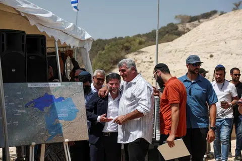 Menteri Kewangan Israel, Bezalel Smotrich (depan paling kiri) berinteraksi dengan seorang lelaki pada hari sidang akhbar mengenai peluasan penempatan bagi projek E1 yang lama dibekukan, yang akan memisahkan Baitulmakdis Timur daripada Tebing Barat yang diduduki, berhampiran penempatan haram Israel Maale Adumim di Tebing Barat yang diduduki Israel, pada 14 Ogos 2025.