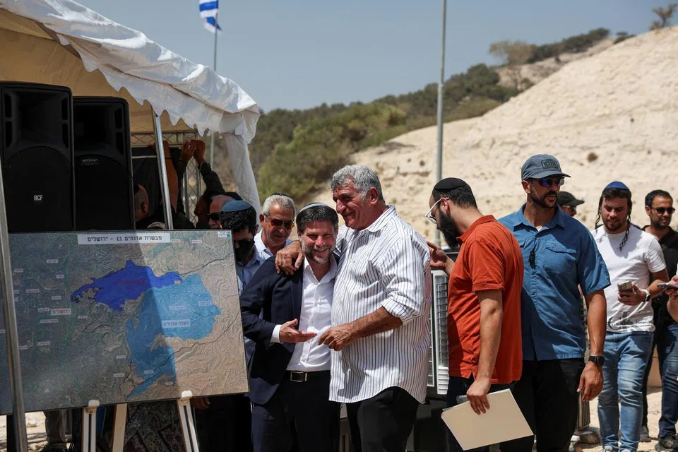 Menteri Kewangan Israel, Bezalel Smotrich (depan paling kiri) berinteraksi dengan seorang lelaki pada hari sidang akhbar mengenai peluasan penempatan bagi projek E1 yang lama dibekukan, yang akan memisahkan Baitulmakdis Timur daripada Tebing Barat yang diduduki, berhampiran penempatan haram Israel Maale Adumim di Tebing Barat yang diduduki Israel, pada 14 Ogos 2025.