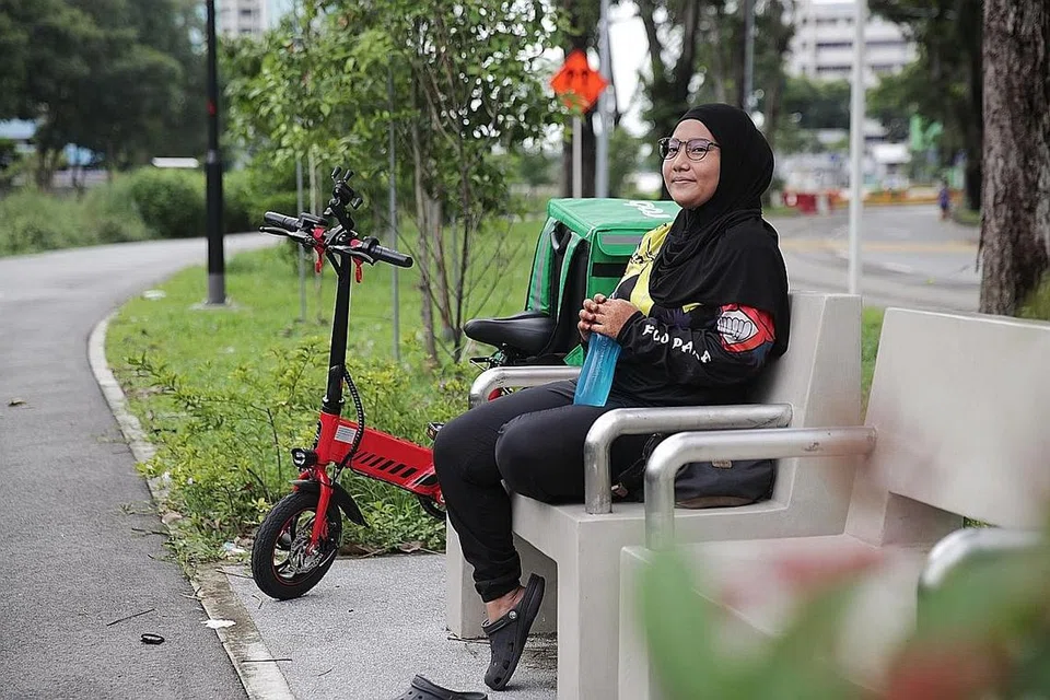 BUAT PENYESUAIAN: Cik Erni Suriyati terpaksa makan atau rehat secara ala kadar dan dengan segera - seperti makan roti semasa mengayuh basikal atau minum air sahaja sebelum menyambung tugas menghantar makanan. - Foto BH oleh GIN TAY