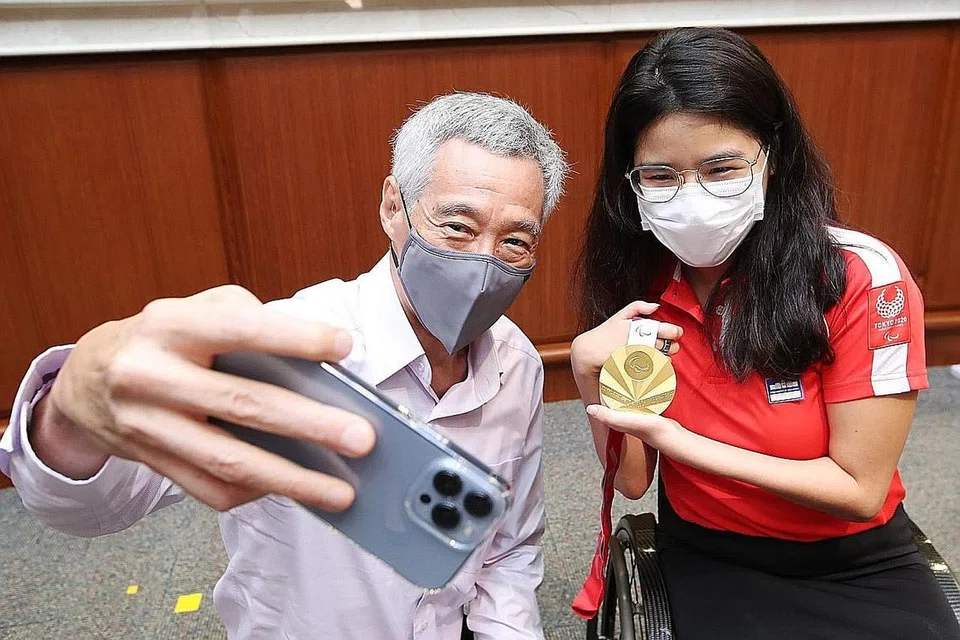 MEMBANGGAKAN: PM Lee bergambar bersama perenang para Yip Pin Xiu di Parlimen semalam. - Foto FACEBOOK/LEE HSIEN LOONG