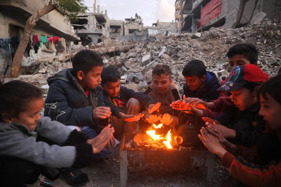 Kanak-kanak menghangatkan diri di Kem Bureij bagi pelarian Palestin pada 30 Disember, di tengah-tengah perang berterusan antara Israel dengan Hamas.