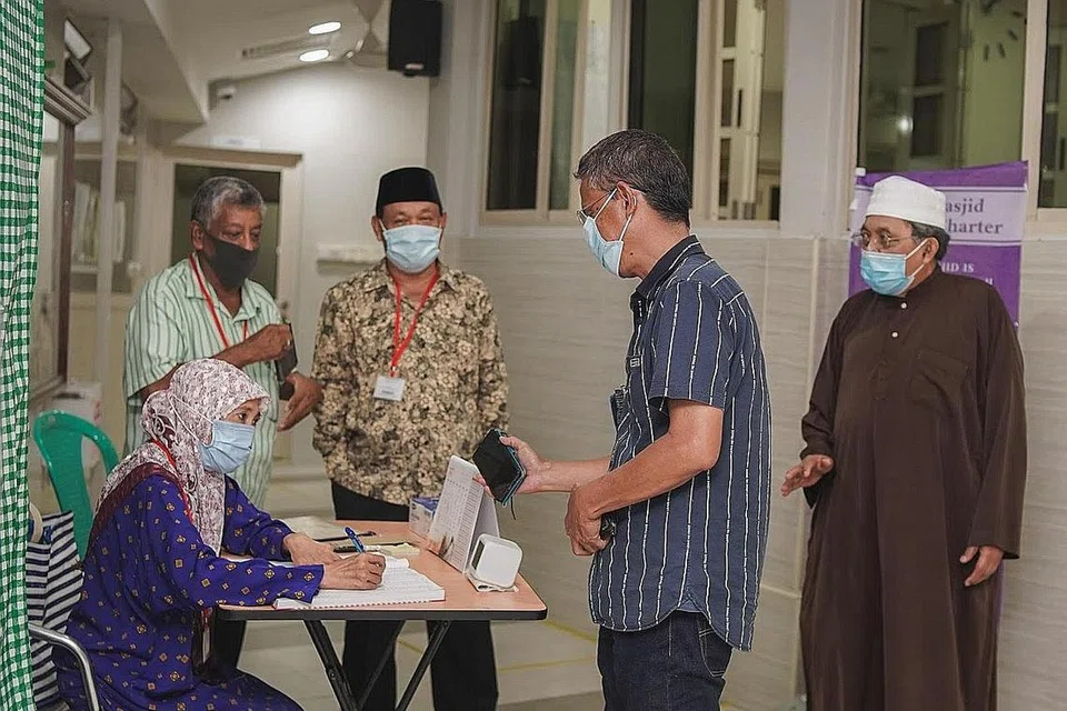 RELAWAN DIPERLUKAN: Imam Masjid Tasek Utara, Ustaz Mohamad Rais (kanan), dan setiausaha Encik Amir Sahat (bersongkok hitam) ada kalanya perlu membantu relawan lain bagi memastikan langkah pengurusan selamat dapat dijalankan dengan lancar bagi jemaah. - Foto BH oleh NUR DIYANA TAHA