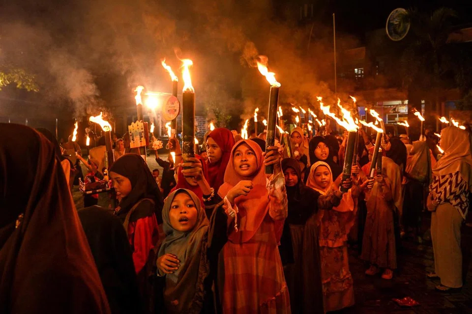 Penduduk mengambil bahagian dalam perarakan obor pada malam Aidilfitri Fitri petanda berakhirnya bulan puasa suci Islam Ramadan, di Surabaya pada 9 April.