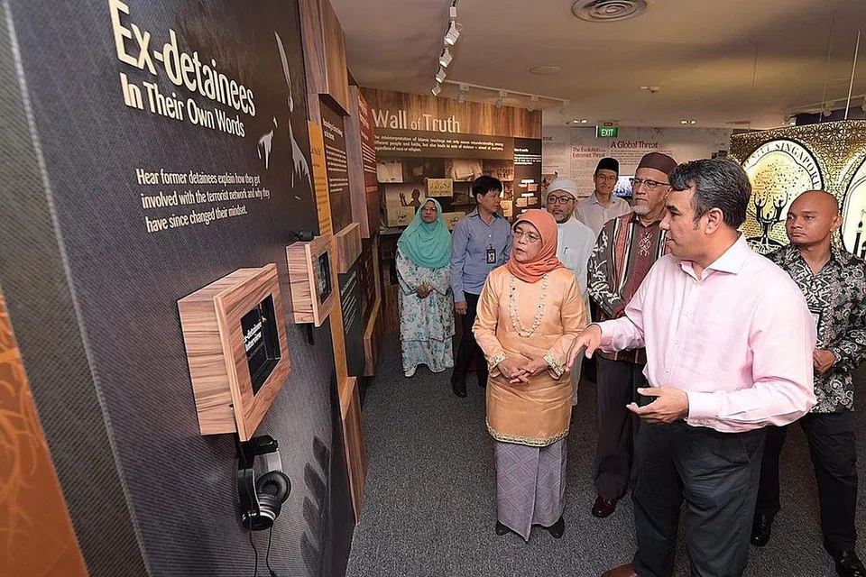 PAPAR PERANAN RRG: Naib pengerusi RRG, Ustaz Dr Mohamed Ali (kanan), menerangkan usaha yang dijalankan RRG kepada Presiden Halimah Yacob, yang ditemani suaminya, Encik Mohamed Abdullah Alhabshee (dua dari kanan), di Pusat Sumber dan Kaunseling RRG pada 2019. - Foto fail