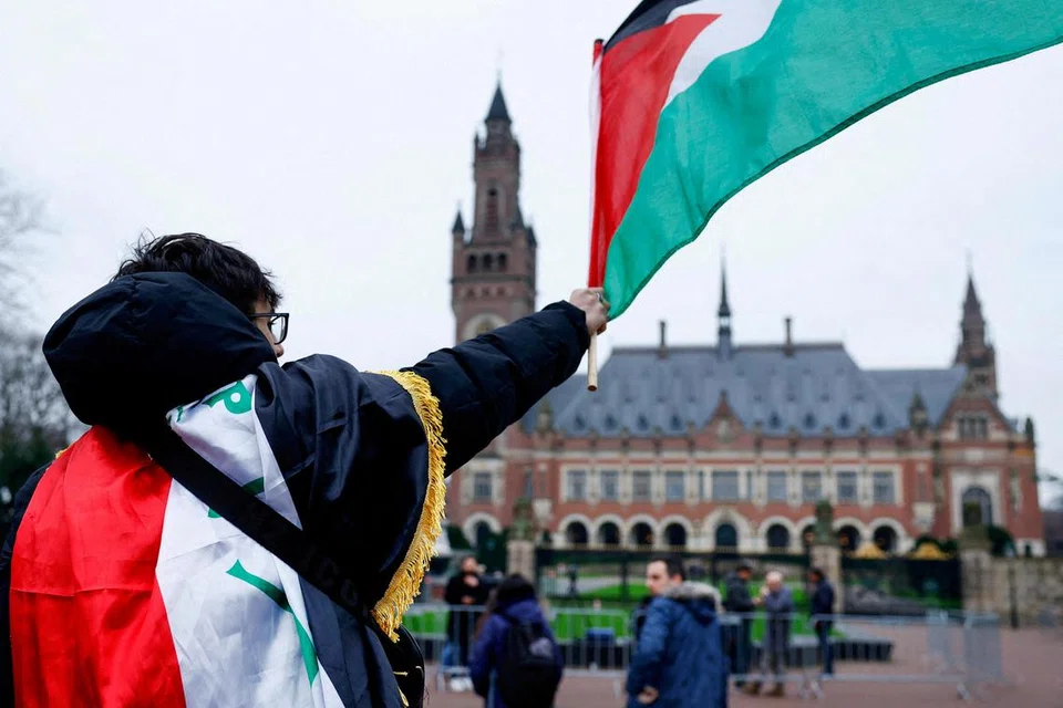Seorang lelaki mengibarkan bendera Palestin di kawasan Mahkamah Keadilan Antarabangsa (ICJ) yang ditubuhkan untuk membuat keputusan dalam pertikaian antara negara dan menjadi pemain utama dalam perang antara Israel dengan anggota Hamas yang meletus selepas serangan 7 Oktober lalu.