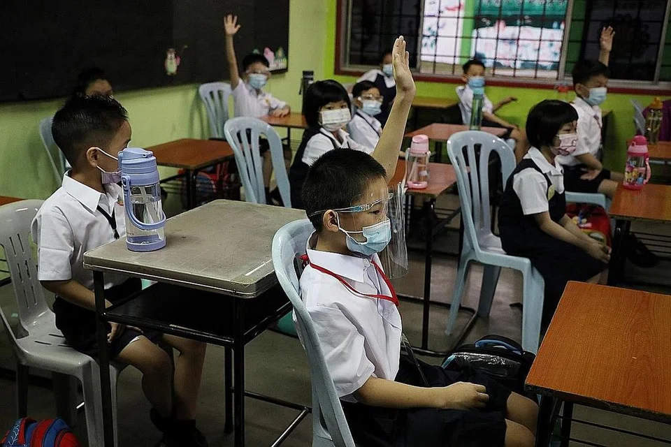 JAGA JARAK: Murid-murid sebuah sekolah rendah di Kuala Lumpur dilihat memakai pelitup dan alat pelindung muka serta mematuhi jarak selamat apabila mereka kembali ke sekolah. - Foto REUTERS